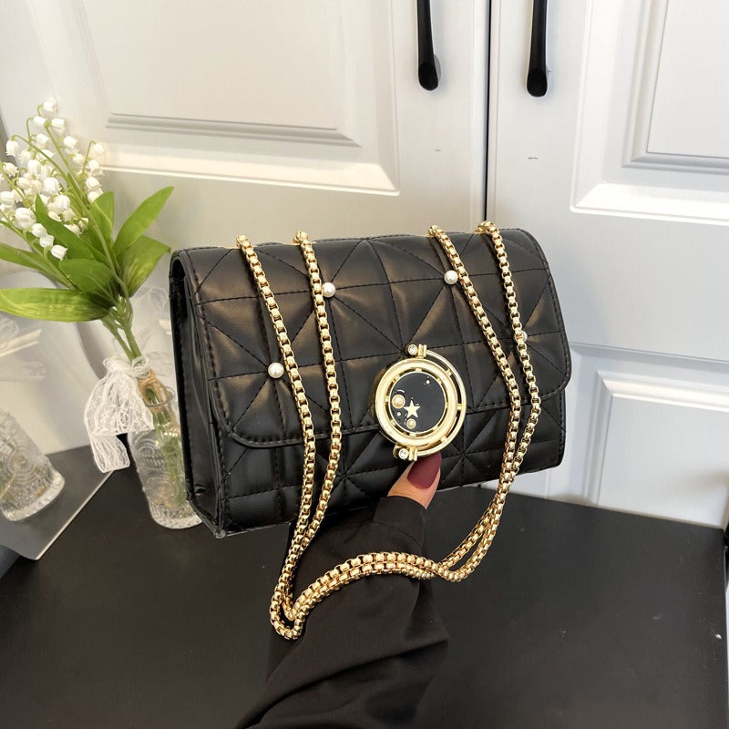 Stylish women's black leather crossbody bag with gold chain and pearl details, perfect for luxurious weddings.