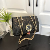 Stylish women's black leather crossbody bag with gold chain and pearl details, perfect for luxurious weddings.