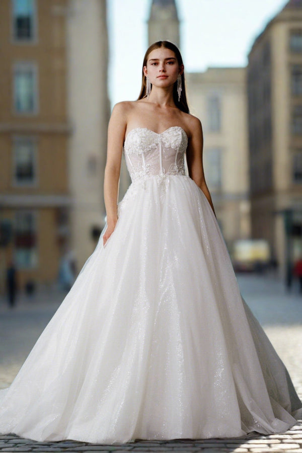a woman in a wedding dress standing on a sidewalk
