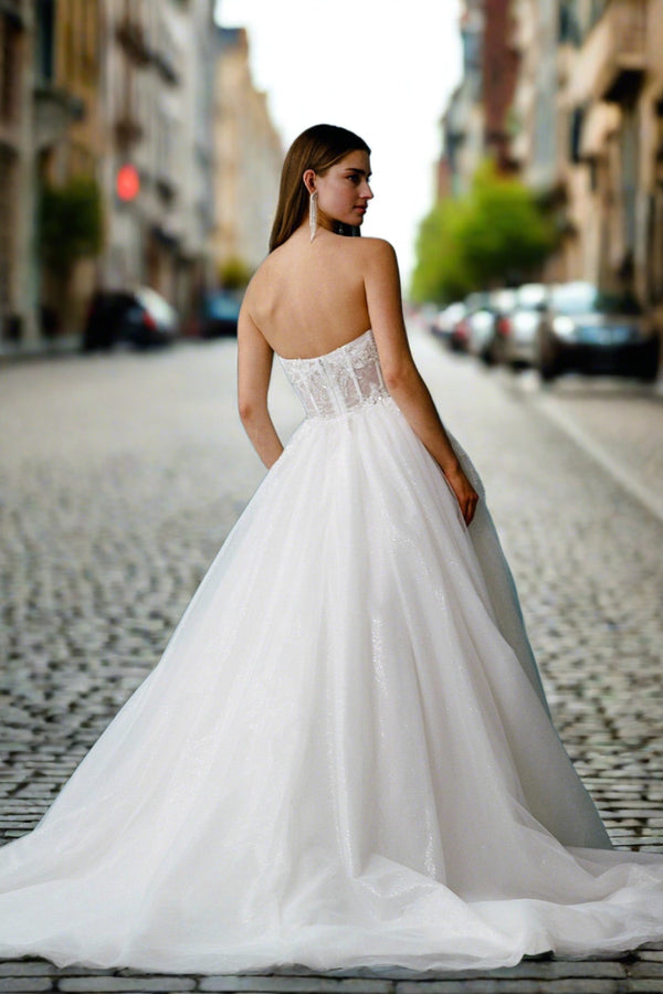 a woman in a wedding dress standing on a cobblestone street
