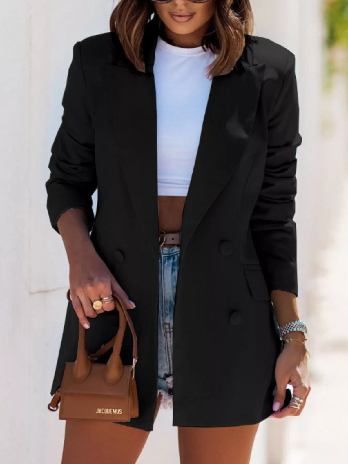 Stylish woman in a black lapel collar long sleeve blazer paired with denim shorts, perfect for luxurious weddings.