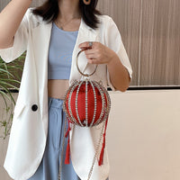 Luxurious red metal ball handbag with diamond accents and tassels, perfect for weddings and elegant occasions.