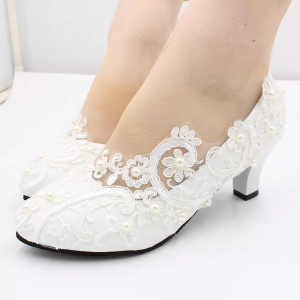 a close up of a woman's white wedding shoes