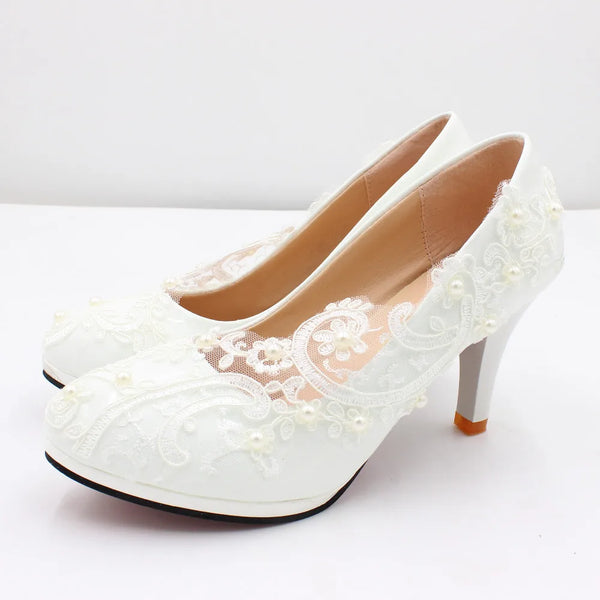 a pair of white high heels with pearls