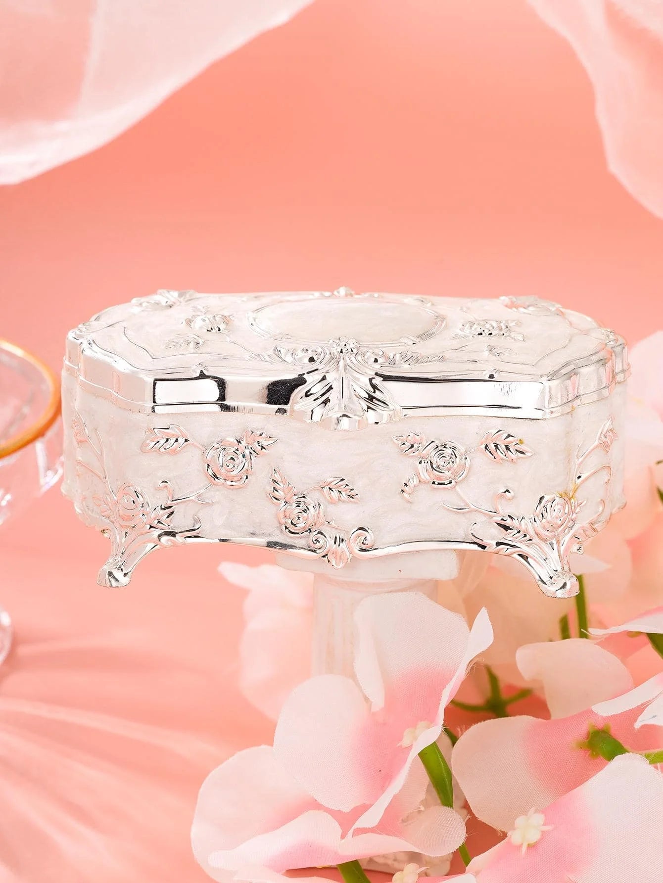 a white box sitting on top of a table next to pink flowers