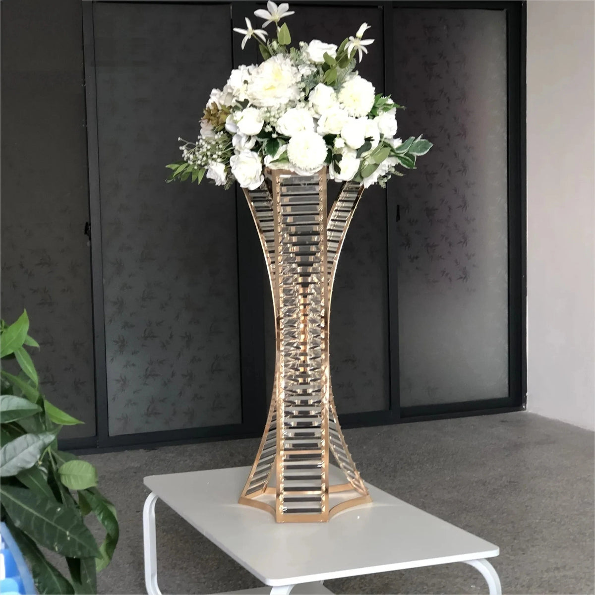 a gold vase with white flowers on a table