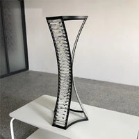 a tall metal vase sitting on top of a white table