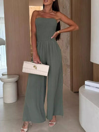 Smocked tube wide-leg jumpsuit in green, styled with a white handbag, perfect for formal wear in NZ.