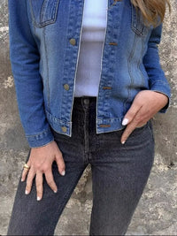 Model wearing a button-front long sleeve denim jacket with black jeans, showcasing a casual and stylish look.
