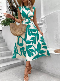 Cutout printed sleeveless dress with green leaf pattern, accessorized with a straw handbag and stylish sandals.