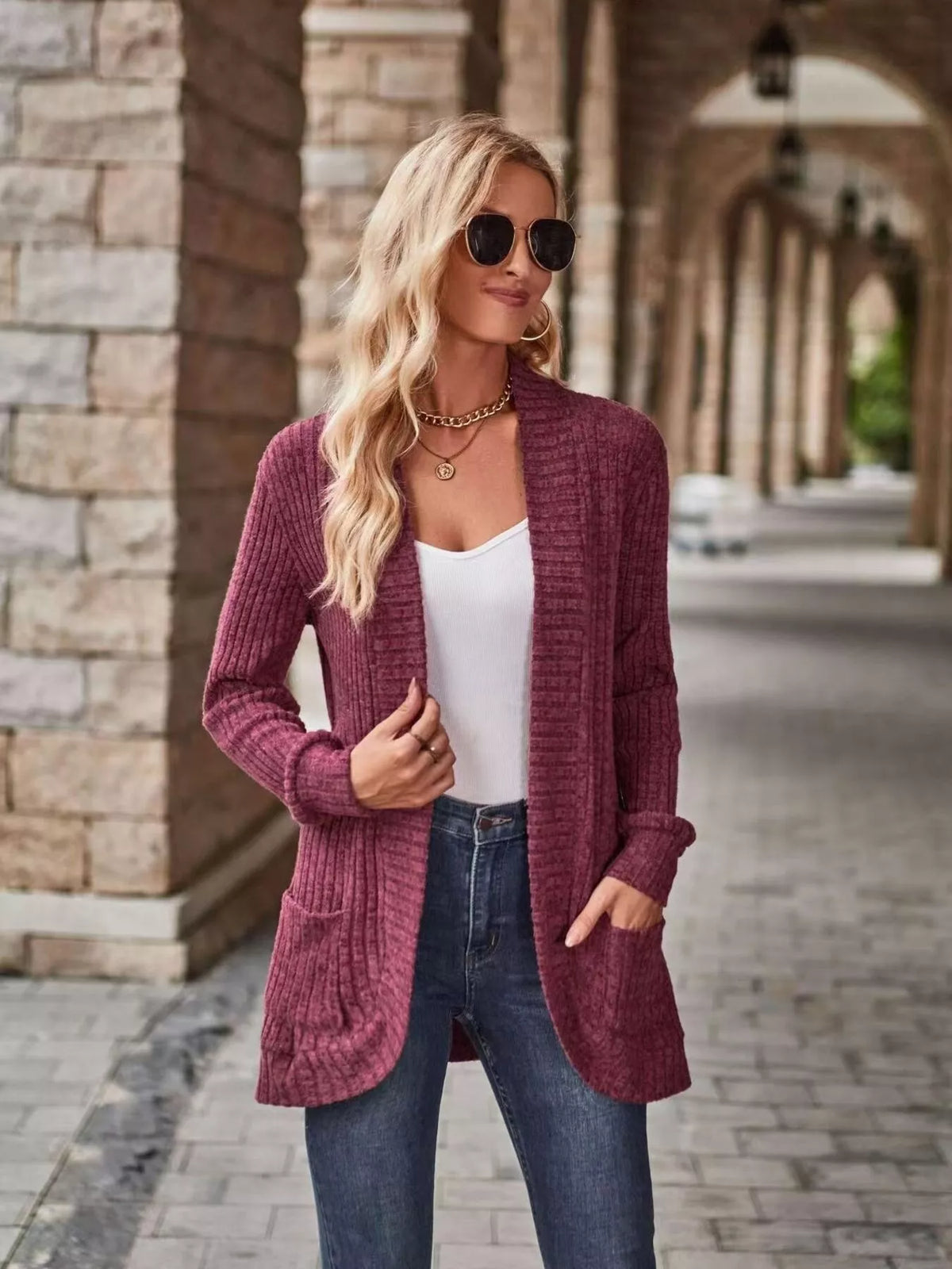 Open front ribbed knit cardigan in burgundy worn by a woman with sunglasses, styled with jeans and a tank top.