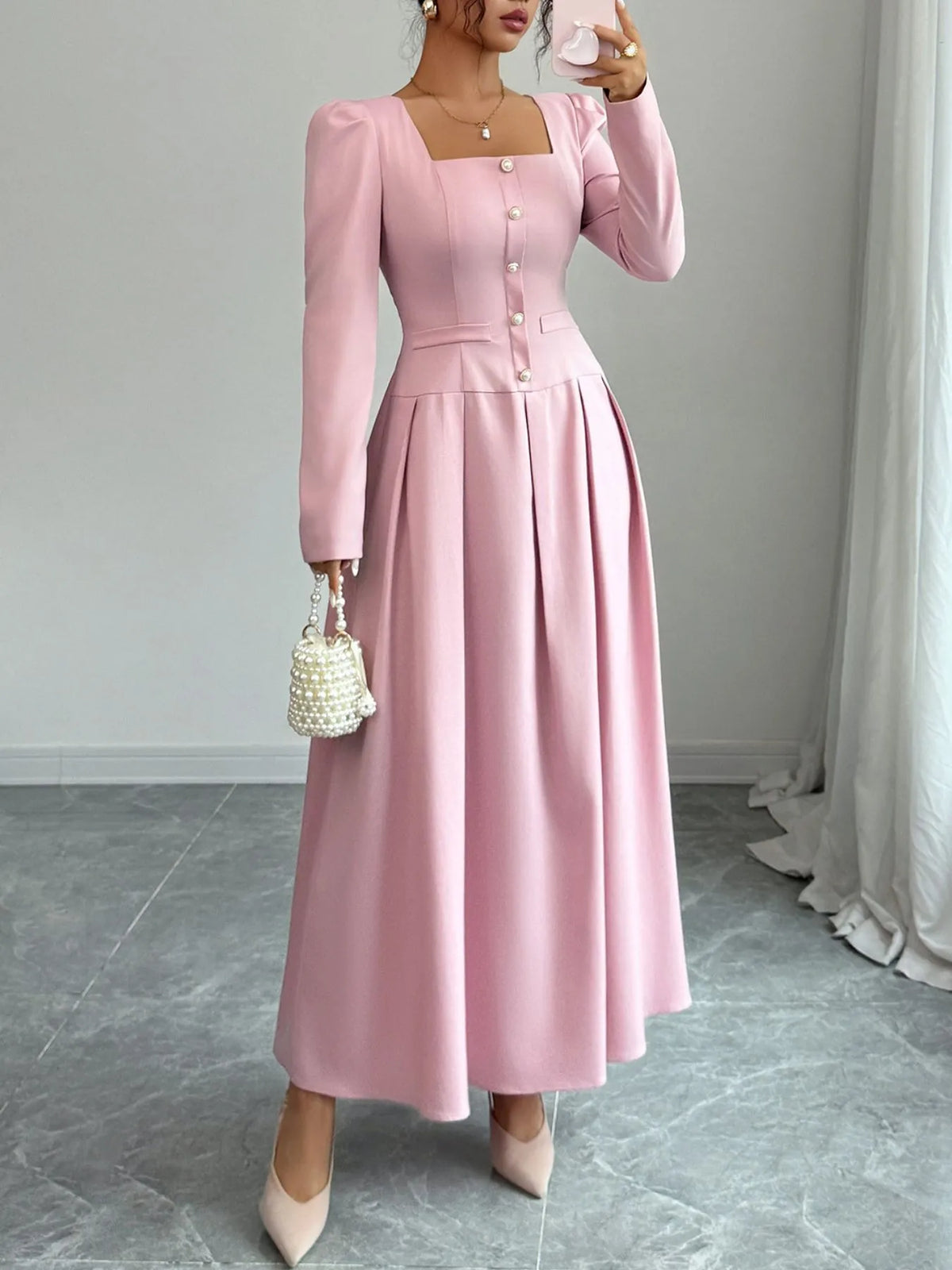 Square neck long sleeve pink maxi dress with decorative buttons, pleated skirt, and elegant silhouette.