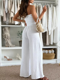 Woman in a smocked tube wide-leg jumpsuit with a handbag, showcasing a stylish formal wear look in NZ.